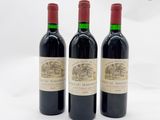 trois bouteilles de vin rouge posées l'une à côté de l'autre sur une surface blanche