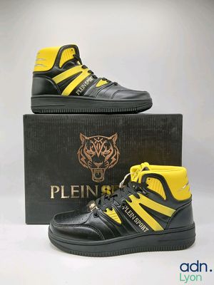 une paire de baskets montantes noires et jaunes dans une boîte