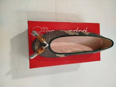 Quelqu'un tient une paire de chaussures posée sur une boîte rouge.