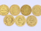 six types différents de pièces d'or sur une surface blanche