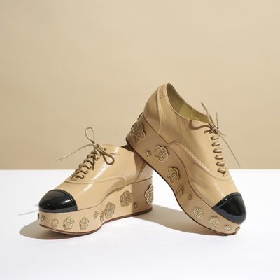 des chaussures en cuir beige à semelles noires sur un fond blanc
