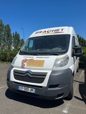 une camionnette blanche garée sur un parking avec des arbres en arrière-plan