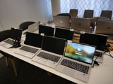 Plusieurs ordinateurs portables sont posés sur une table devant une rangée de chaises