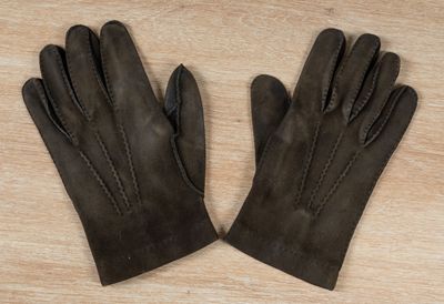 a pair of brown leather gloves sitting on top of a wooden table
