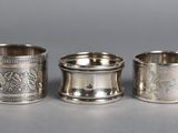three silver napkins with designs on them sitting on a table