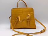 a yellow handbag with a strap on a white background