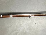 un fusil accroché au mur, sur lequel est posé un couteau
