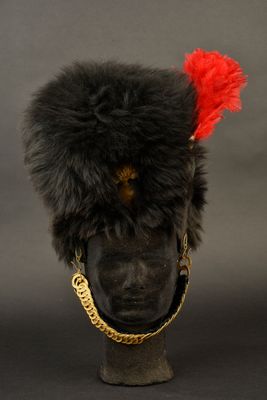 un vieux chapeau noir orné d'une plume rouge, posé sur la tête d'un mannequin