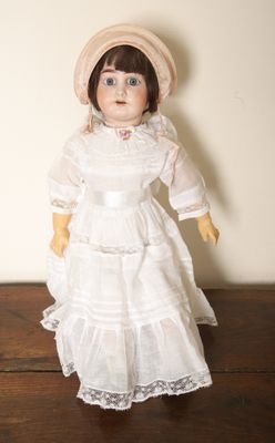 une poupée qui porte une robe blanche et un chapeau