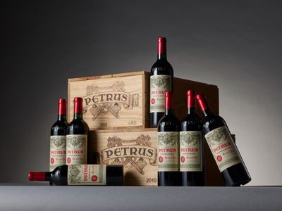 trois bouteilles de vin rouge sont posées devant une caisse en bois