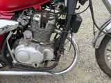 a red motorcycle parked on a gravel road next to another motorcycle