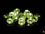 a close up of a bunch of green gems on a black surface