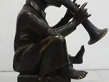 statue of a man playing a trumpet sitting on a black base