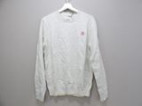 a white sweater hanging on a hanger on a wall