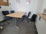 a woman sitting at a table in a room with chairs