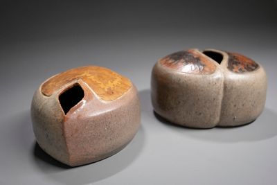 two small vases with holes in them on a table