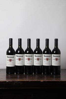 six bouteilles de vin rouge sont alignées sur une table en bois
