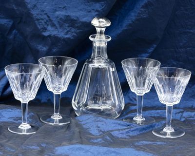 four wine glasses and a decanter on a table