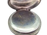 a silver pocket watch sitting on a white surface