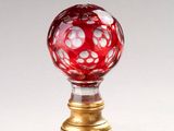une boule de verre rouge posée sur un socle doré