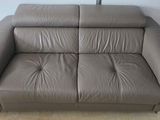grey leather sofa in a room with clothes hanging on the wall