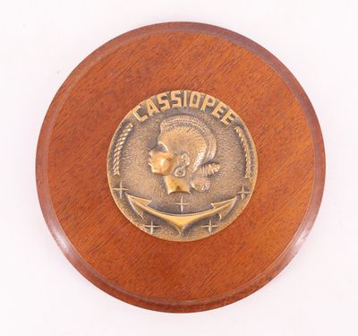 une photo d'une plaque en bois sur laquelle est apposé un médaillon en bronze