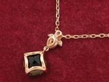 a close up of a gold necklace with a black stone on it