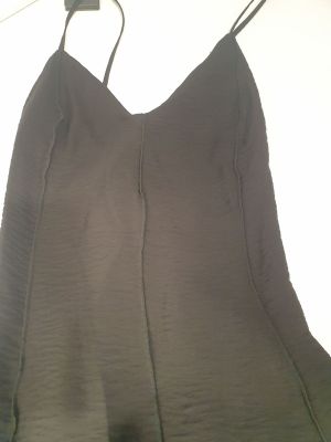 le dos d'une robe noire suspendue à un cintre sur un mur blanc