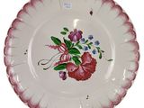 une assiette décorée de fleurs, posée sur un socle