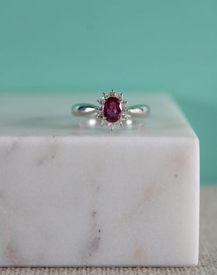 une image représentant une bague ornée d'un rubis posée sur un bloc de marbre blanc