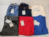 Cinq paires de jeans pour homme sont disposées sur une surface blanche