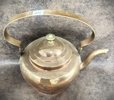 a gold tea pot with a handle on a table