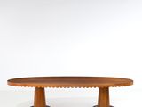 une table ovale en bois aux bords festonnés, sur fond blanc
