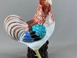 une figurine représentant un coq debout sur une souche d'arbre