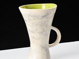 a white and green cup sitting on a white table