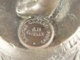 a silver statue of a bird with a coin on it ' s neck