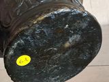 a black vase sitting on a wooden table with a yellow sticker on it