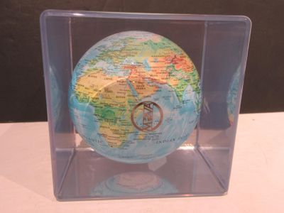 un petit globe terrestre dans une boîte transparente posée sur une table