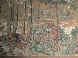 a tapestry with a picture of a man riding a horse in the woods