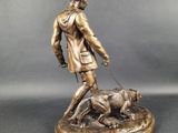 a bronze statue of a man walking a dog on a leash