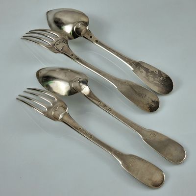 quatre cuillères et deux fourchettes sur une table blanche