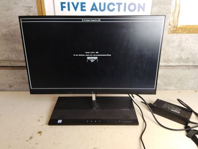 un écran d'ordinateur posé sur un bureau, avec un chargeur