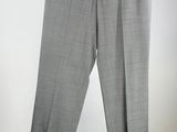 grey pants hanging on a hanger against a white wall