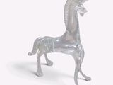 un cheval en verre posé sur une surface blanche