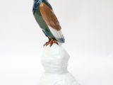 statue of a bird sitting on top of a rock on a white surface