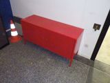 une armoire rouge dans un coin de la pièce, à côté d'un cône de signalisation