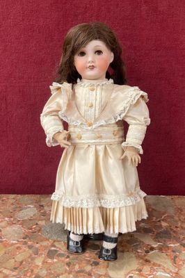 une poupée ancienne représentant une jeune fille vêtue d'une robe blanche et de chaussures noires