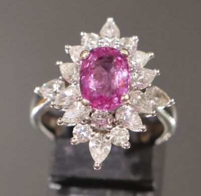 une photo d'une bague sertie d'un saphir rose et de diamants, posée sur un fond noir
