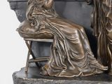 a bronze statue of a woman sitting on a chair