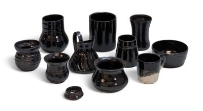 de nombreux vases et tasses noirs posés sur une surface blanche